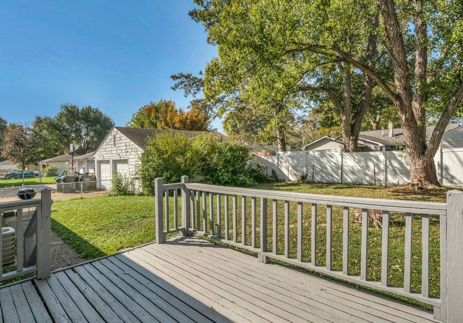 Wood backyard deck with white railings overlooking a green lawn