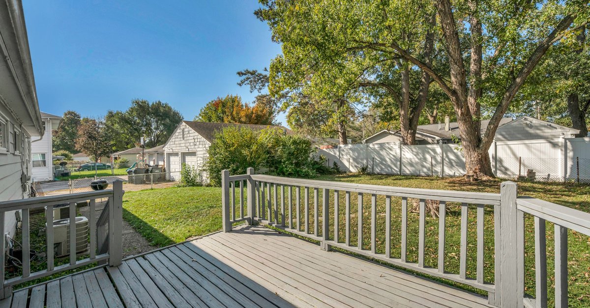 Wood backyard deck with white railings overlooking a green lawn